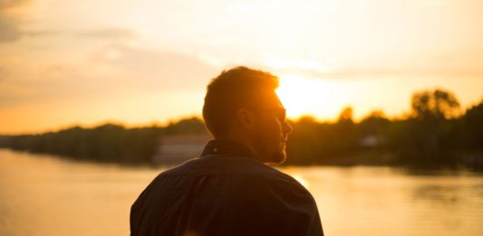 Billig-hårtransplantation tilbyder hårtransplantationer til halvdelen af prisen i Danmark Mand står og kigger ud mod solnedgang over sø