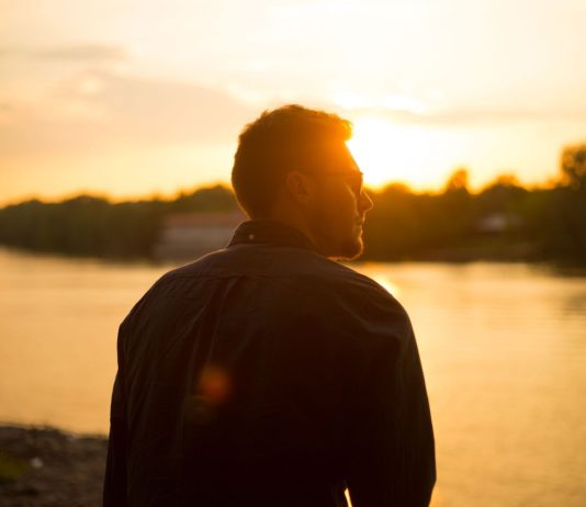 Billig-hårtransplantation tilbyder hårtransplantationer til halvdelen af prisen i Danmark Mand står og kigger ud mod solnedgang over sø